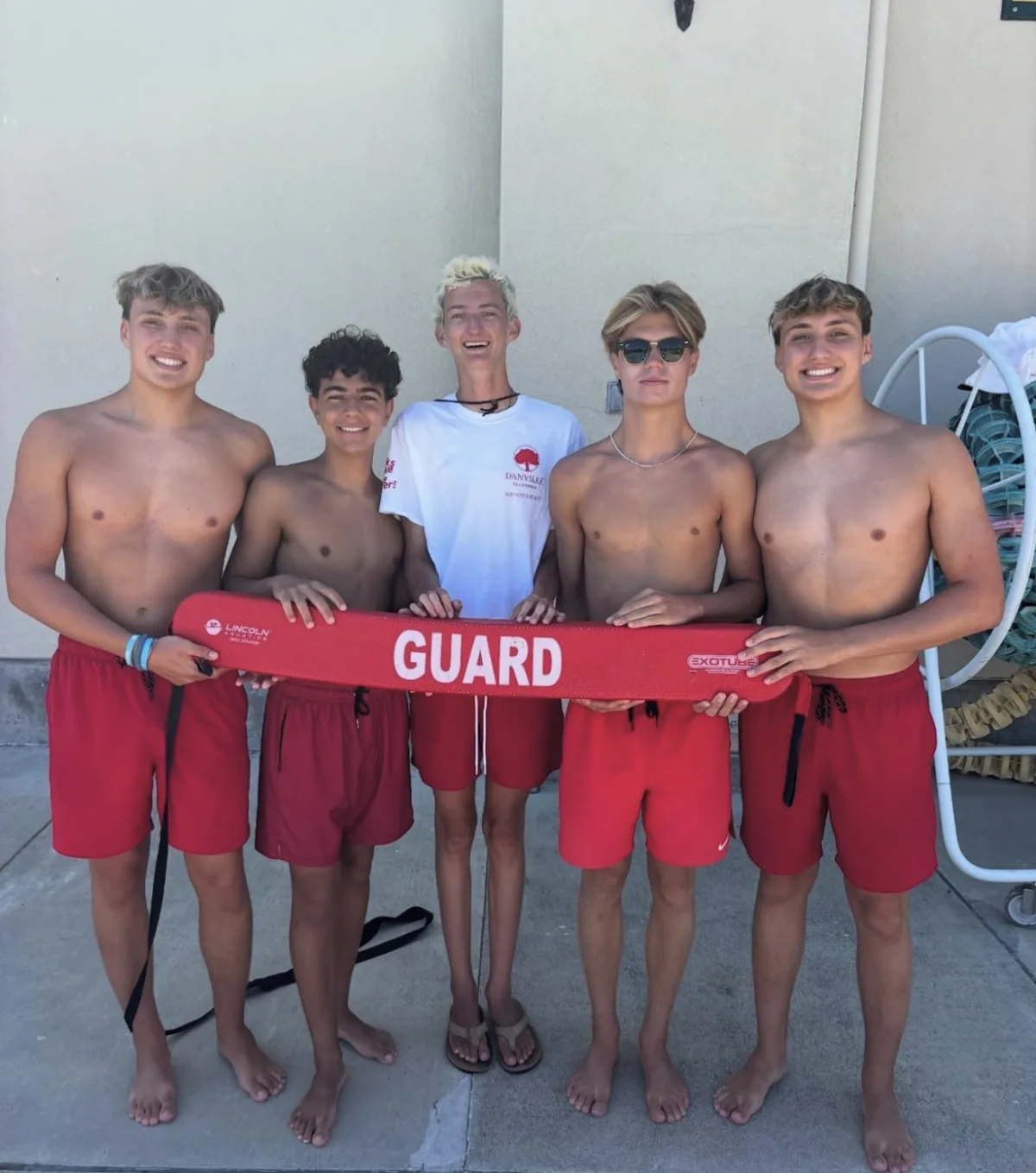 Five members of the lifeguard team holding a red rescue float